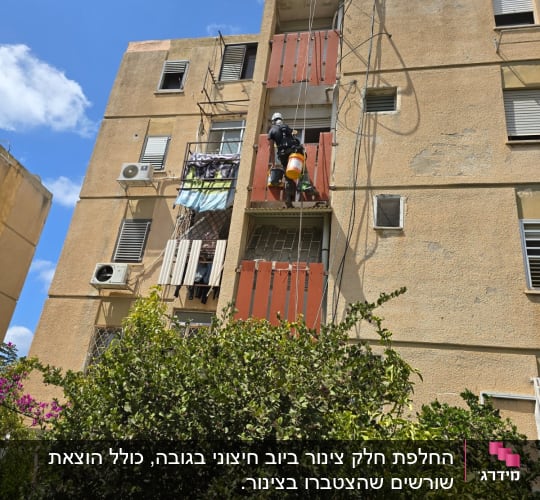 אדם עובד בגובה על בניין עם ציוד בטיחות
